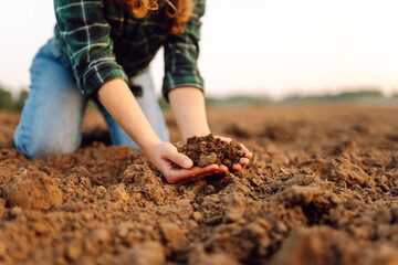 Female farmer hands holding black soil in their hands. Fertile land. garden field ground fertile...