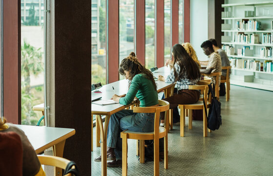 Young group of people studying inside college university library - Back to school and education concept - Focus on center girl with green jersey