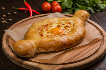 khachapuri with sulguni cheese, herbs and egg on a wooden surface. Georgian pie. Georgian pizza
