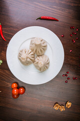 khinkali with meat, mushrooms and potatoes, herbs on a white plate