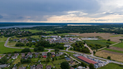 Drone photography of small town near lake surrounded by forest during summer dusk