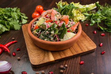 Georgian Tbilisi style salad with tomatoes, cucumbers and meat on a wooden table