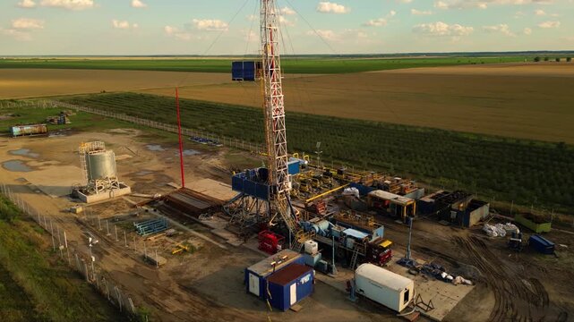 Aerial shot of shale gas drilling rig in a rural field in Romania. Fracking drill seen from above in the middle of a crop field. Drone footage of Hydraulic fracturing construction site.
