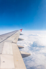 View from the airplane window at a beautiful cloudy sky and the airplane wing