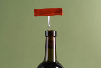 Wine bottle with corkscrew on olive background, closeup