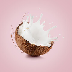 coconut with palm leaf and milk splash on a light pink background
