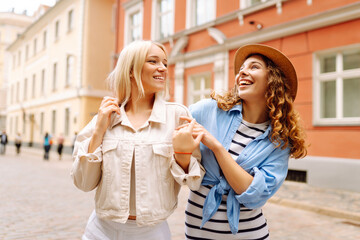 Two women having fun walking in city street - Happy young women laughing together enjoying summertime vacation. Concept of lifestyle, fashion, travel.