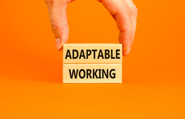Adaptable working symbol. Concept words Adaptable working on beautiful wooden block. Beautiful orange paper background. Businessman hand. Business Adaptable working concept. Copy space.