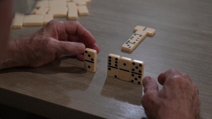 senior citizen playing dominoes places a domino on the table as his next game move