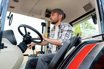 Naklejka premium Young adult male operates farm or construction tractor.