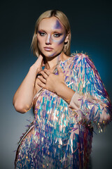 A stylish young woman showcases a holographic ensemble with artistic makeup.