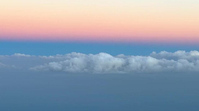 Aerial airplane view of drifting clouds during sunrise with Belt of Venus and earth shadow, terminator dividing day and night in pink color.