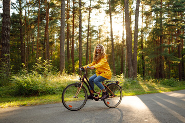 Happy woman rides a bicycle in a sunny autumn park. Healthy lifestyle on leisure activity.