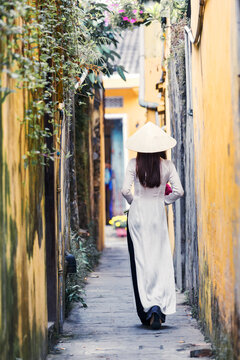Young vietnamese girl with traditional white dress walking in a alley, Hoi An, Vietnam
