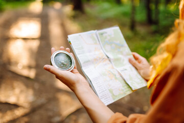 Traveler explorer young woman holding compass and a map in her hands on the forest. Adventure, vacation concept. Active lifestyle.