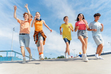Happy teenagers boy and girls in colorful t shirts running enjoying summer vacation