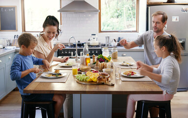 Happy family, kitchen table and eating breakfast for nutrition, food and meal as healthy diet in morning. Parents, children and house with excited, hungry and together on weekend for bonding in home