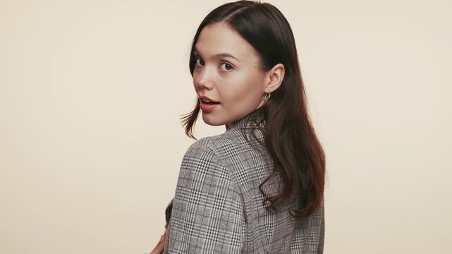 A young woman in a houndstooth blazer poses confidently, exuding a sense of pride and style with a pleasant smile.