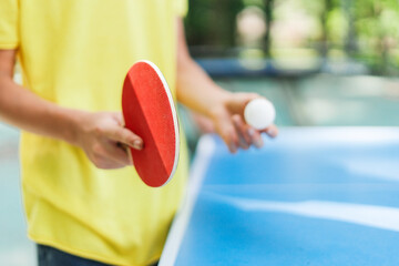 Boy holding racket and table tennis ball, going to play outdoors