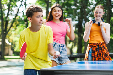 Smiling boy holding racket and ball for ping pong outdoors