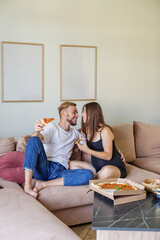 Happy Couple Enjoying Pizza on Couch. Family time.