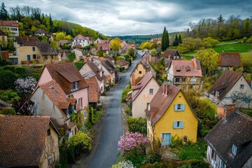 Obraz premium Bird's-eye view of a European village in spring, with pastel-colored houses and blooming flowers lining the streets.