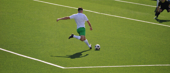 Football player in green and white equipment making a shot towards the goal