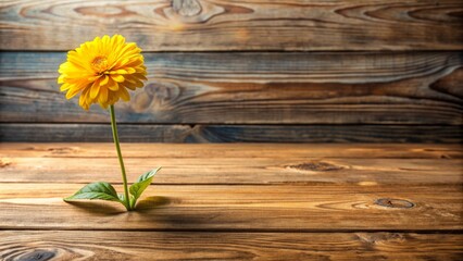 Obraz premium A rustic wooden table centered with a vibrant yellow flower and fresh green stem set amidst a minimalist background evoking a sense of serenity.