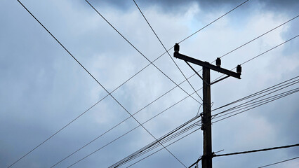 A utility pole with numerous wires set against a cloudy sky, rural infrastructure and the overcast weather