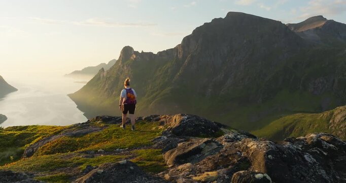 Hiker wander in arctic Norway mountain reveal majestic fjord in vibrant sunset