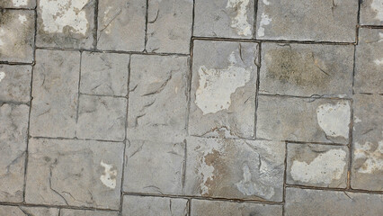 Weathered stone pavement featuring wet patches and natural texture, highlighting the effects of rain and wear