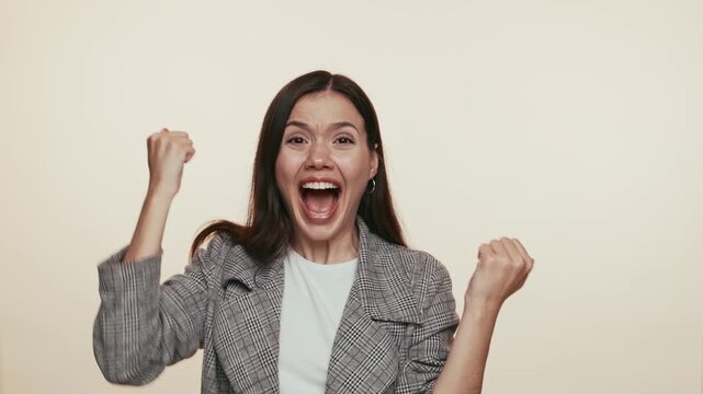 An exuberant businesswoman with raised fists, symbolizing success and victory in a professional setting.