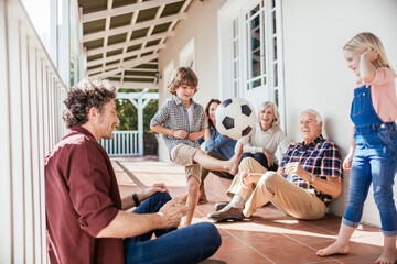 Multigenerational family playing soccer on house porch