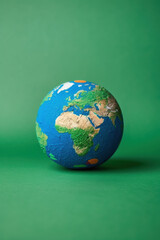 Fototapeta premium A detailed miniature globe showing continents against a green background, emphasizing geography, global awareness, and environmental themes.