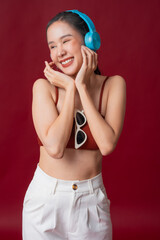 Fototapeta premium stylish active asian woman wear sport casual dress and listening music headphone wellnes healthy lifestyle studio shot portrait on red color background happiness cheerful woman in action concept