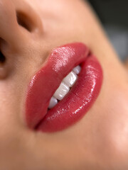 permanent makeup on the lips of a young woman of a delicate peach shade close-up, a girl after a...