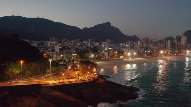 Nighttime aerial view of Leblon in Rio de Janeiro, Brazil, showing the illuminated beach and buildings.