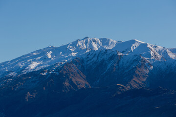 Fototapeta premium Zoom in view of snowy mountains on a clear sky.
