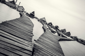 A network of weathered wooden piers leads to quaint cabins floating on the tranquil waters of Bokodi Lake in Hungary.