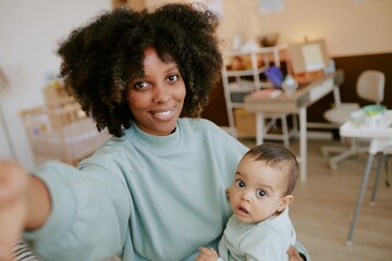 African American blogger mom taking selfie with her baby boy in nursery