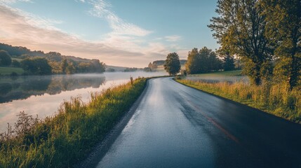 Fototapeta premium A peaceful road along a calm river, with reflections and a serene atmosphere, perfect for a tranquil message.