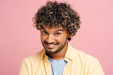 Obraz premium Young Indian man with curly hair smiling on pink background