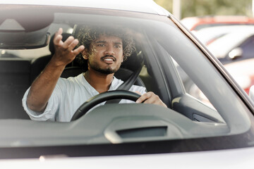 Young man getting angry while driving and gesturing through windshield