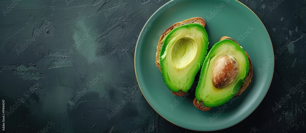 Poster Top view of two avocado toast slices on a dark background displayed on a turquoise plate providing copy space image