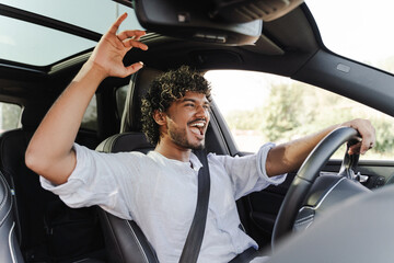 Happy Indian man driving car and singing along to music