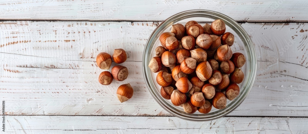 Poster hazelnuts without shells in a glass bowl on a white wooden surface exemplifying healthy eating with 