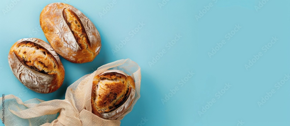 Poster flat lay with copy space image of mesh bag holding freshly baked bread on a blue background