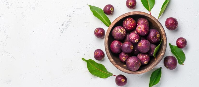 Ripe phalsa fruit in a wooden bowl with leaves isolated on a white background emphasizing a top view with selective focus and copy space image