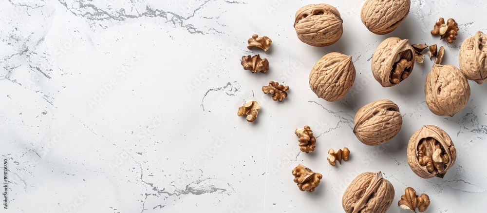 Poster Top down view of walnuts in shells on a white stone surface ideal for adding text to the image. Creative banner. Copyspace image