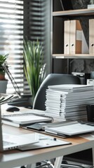 Fototapeta premium A modern office featuring stacked notebooks, a laptop, and greenery in bright daylight
